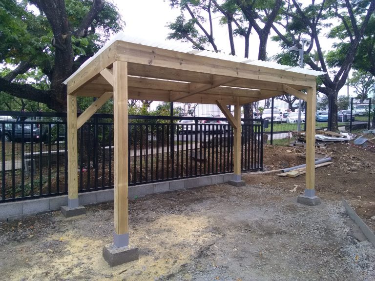 Pergola en bois fraîchement posée sur un terrain clôturé