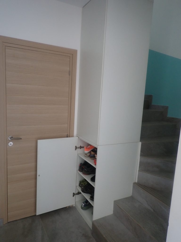 Meuble à chaussures intégré au départ d'un escalier