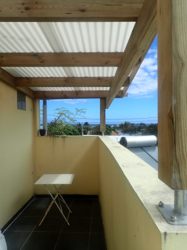 Auvent en bois couvert de tôle ondulée sur un balcon